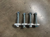 Four metal expansion anchor bolts with hex nuts and flat washers, arranged in a row on a textured concrete floor. diff drops